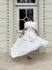 Woman in a white dress standing in front of a door.