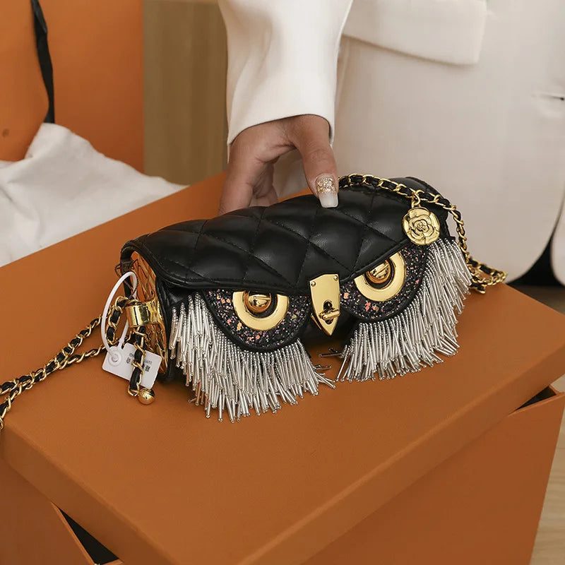 Hand holding black quilted owl chain bag