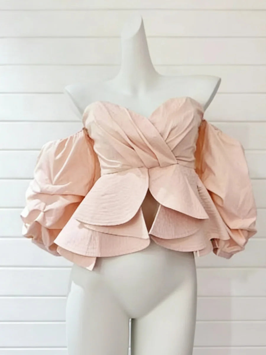 Pink ruffled top on a mannequin against a white background