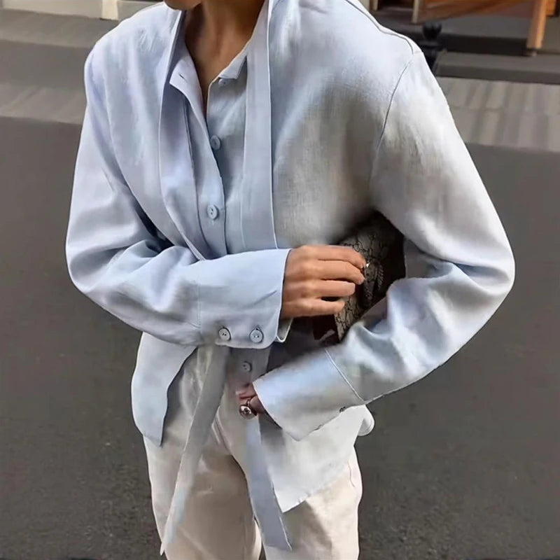 Person wearing a light blue oversized shirt with a blurred background