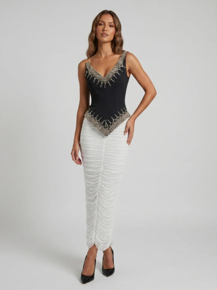 Model wearing a black beaded V-neck sleeveless top and a white ruched floor-length skirt.