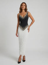 Model wearing a black beaded V-neck sleeveless top and a white ruched floor-length skirt.