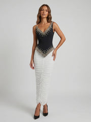 Model wearing a black beaded V-neck sleeveless top and a white ruched floor-length skirt.