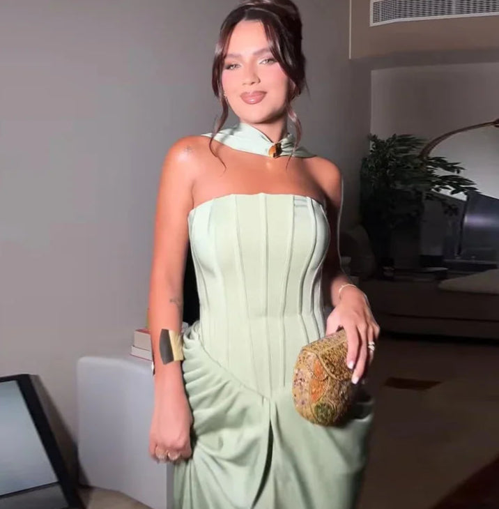 Woman in a light green strapless dress holding a clutch in an indoor setting