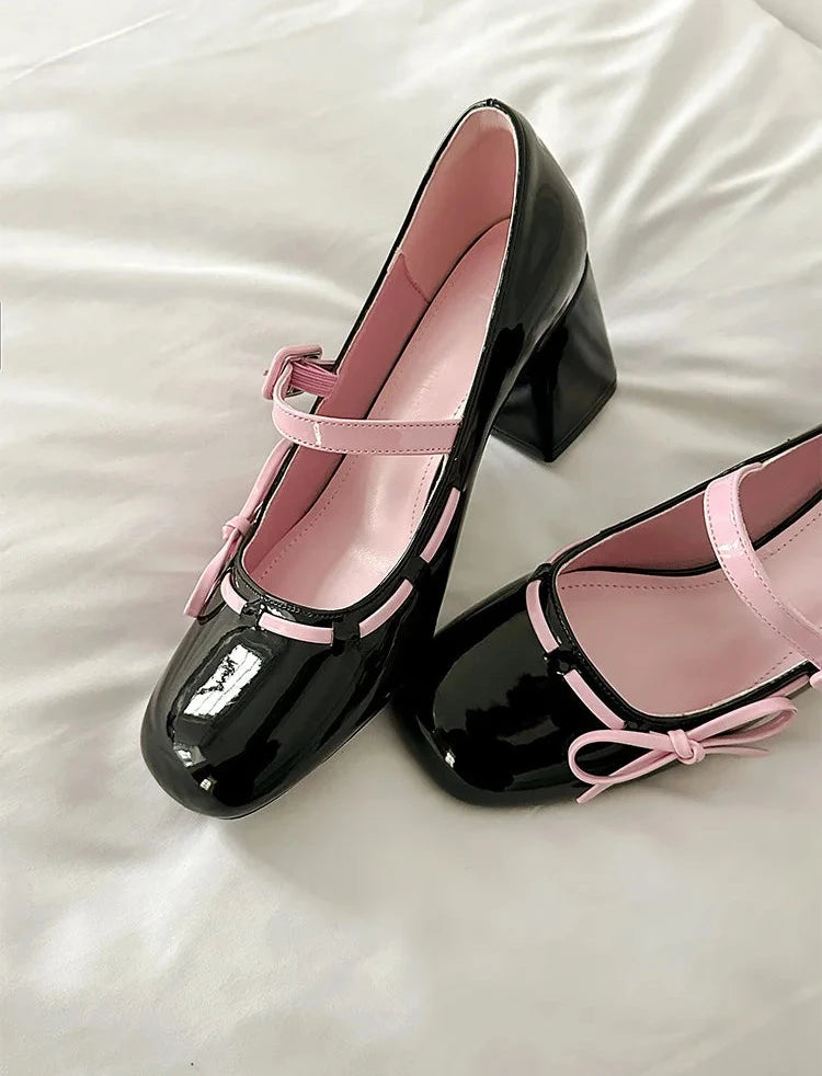 Close-up of black patent leather chunky Mary Jane heels on a white surface.