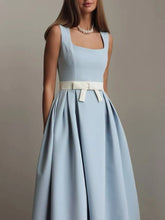 Light blue dress with a white belt worn by a model against a neutral background