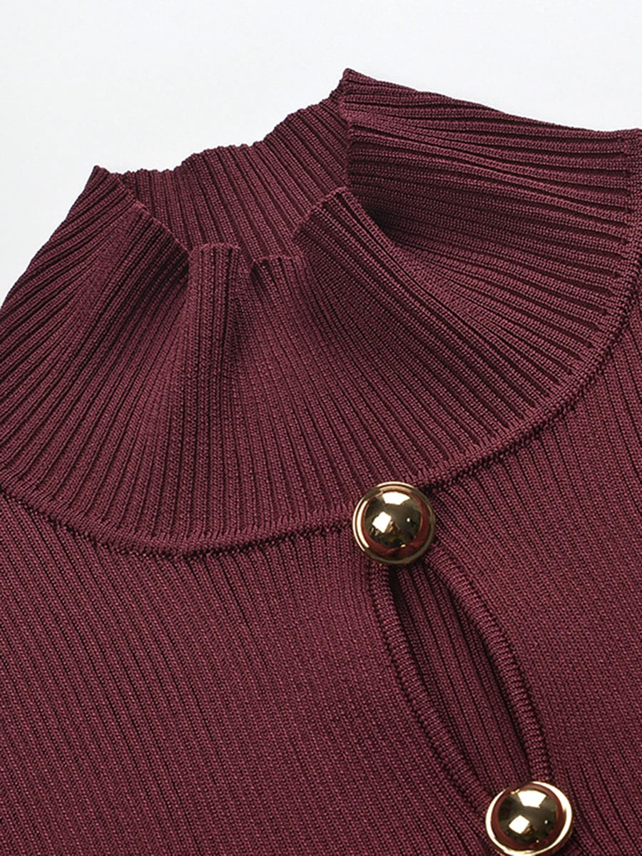 Close-up of a ribbed knit sweater with a button detail on a plain background