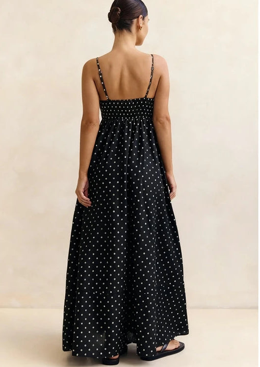 Woman wearing a black polka dot dress against a beige background