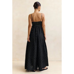 Woman wearing a black polka dot dress against a beige background