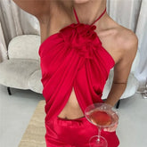 Red halter crop top with ruffled flower detail and draped asymmetric hem.