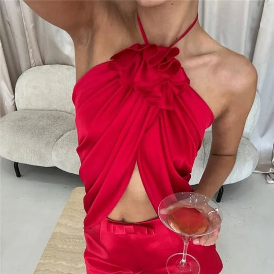 Red halter crop top with ruffled flower detail and draped asymmetric hem.