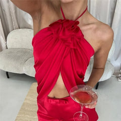 Red halter crop top with ruffled flower detail and draped asymmetric hem.