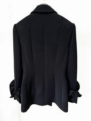 Back view of a sculpted double-breasted black blazer with floral cuff details.