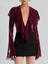 Maroon lace top with long sleeves and a black skirt on a plain background