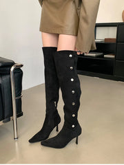 Black knee-high boots with pearl buttons worn by a person in a room.