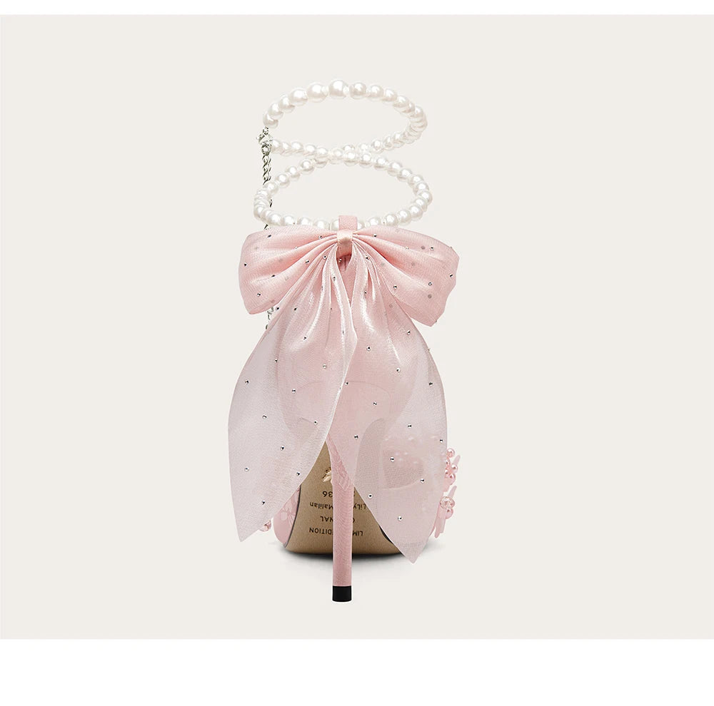 Pink bow-shaped handbag with pearl handle on a white background