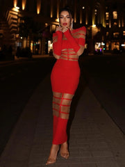 Woman in a red dress with cut-out design standing on a street at night.