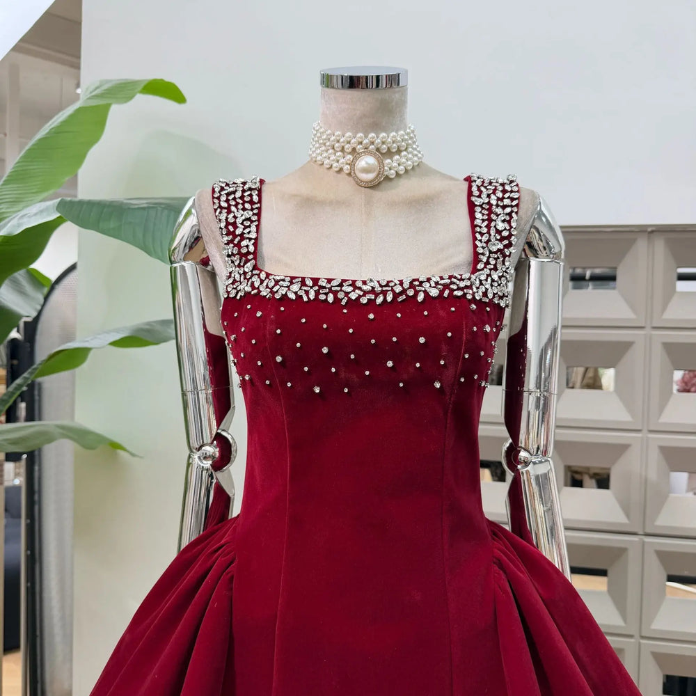 Red evening gown with pearl embellishments on a mannequin against a neutral background.
