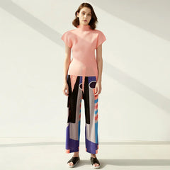 Woman wearing a pink top and colorful pants on a white background