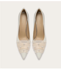 Pair of beige high-heeled shoes with pearl embellishments on a white background
