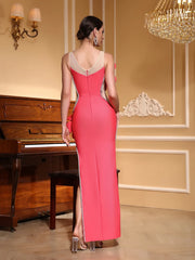 Woman in a pink evening gown standing in an elegant room with a piano and chandelier.