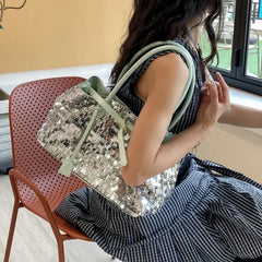 A person wearing a striped dress carries a sequin tote bag