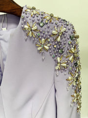 Elegant dress with floral beaded shoulder detail on a plain background