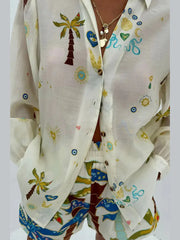 White shirt with colorful palm tree and beach-themed designs on a plain background