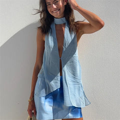 Woman wearing a light blue sleeveless dress against a white wall