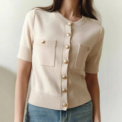 Beige cardigan with gold buttons worn by a person on a plain background