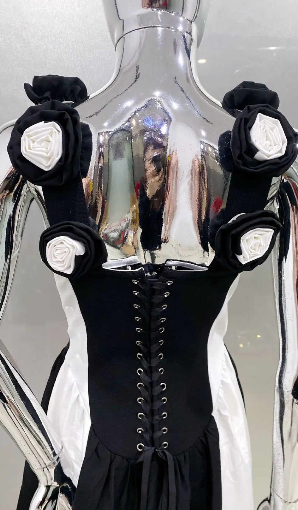 Black dress with floral arm cuffs in front of a reflective surface