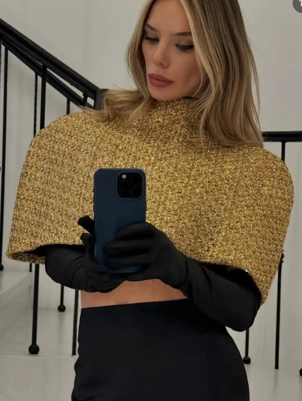 Woman wearing a gold sequin top and black gloves holding a phone.