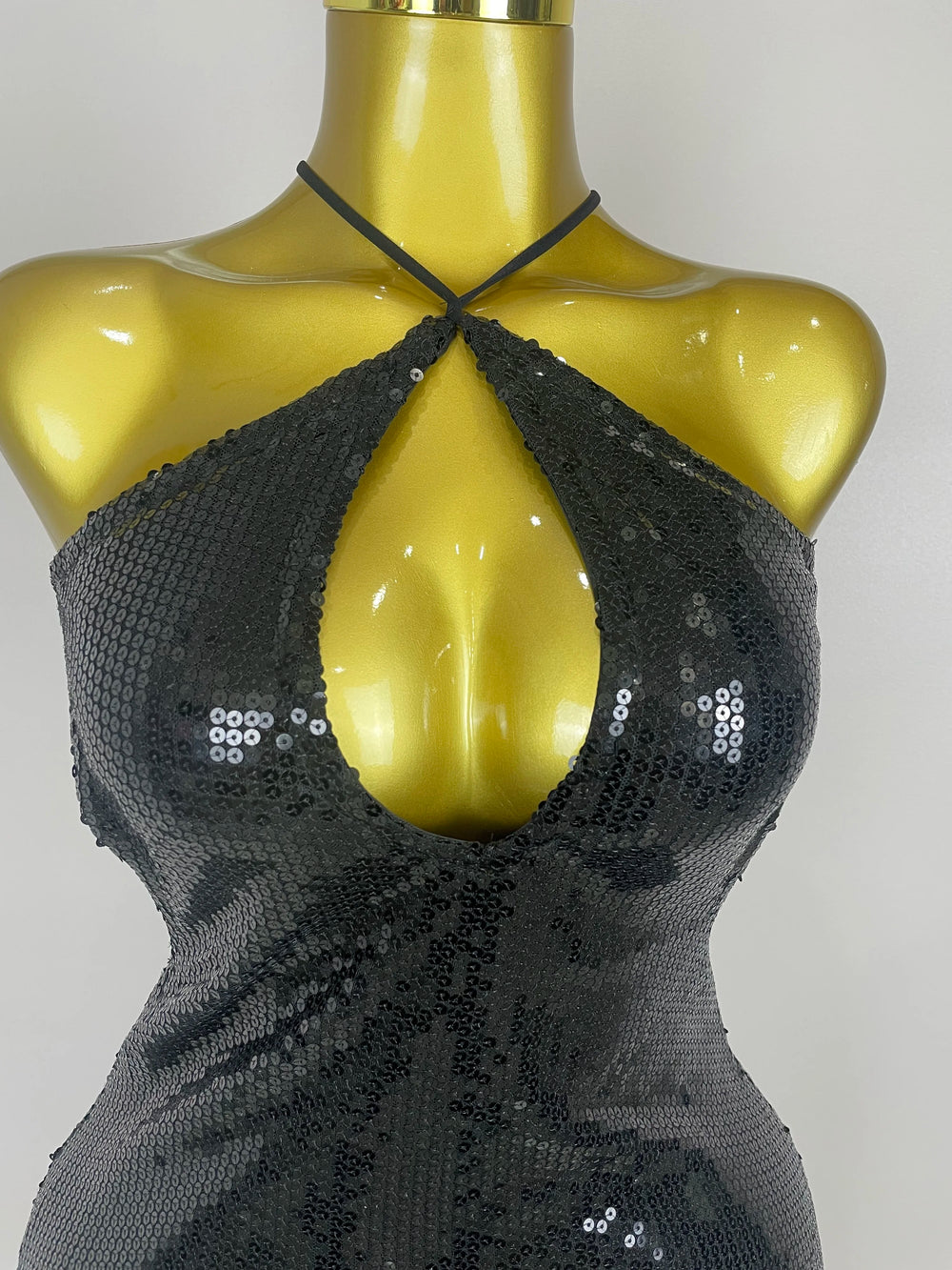 Black sequin top on a mannequin against a plain background