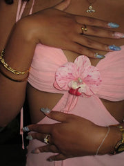 Close-up of a person wearing a pink strapless top with floral details.