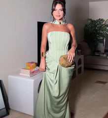 Woman in a light green strapless dress holding a clutch in an indoor setting.