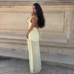 Woman in a light yellow dress standing on steps with a neutral wall background