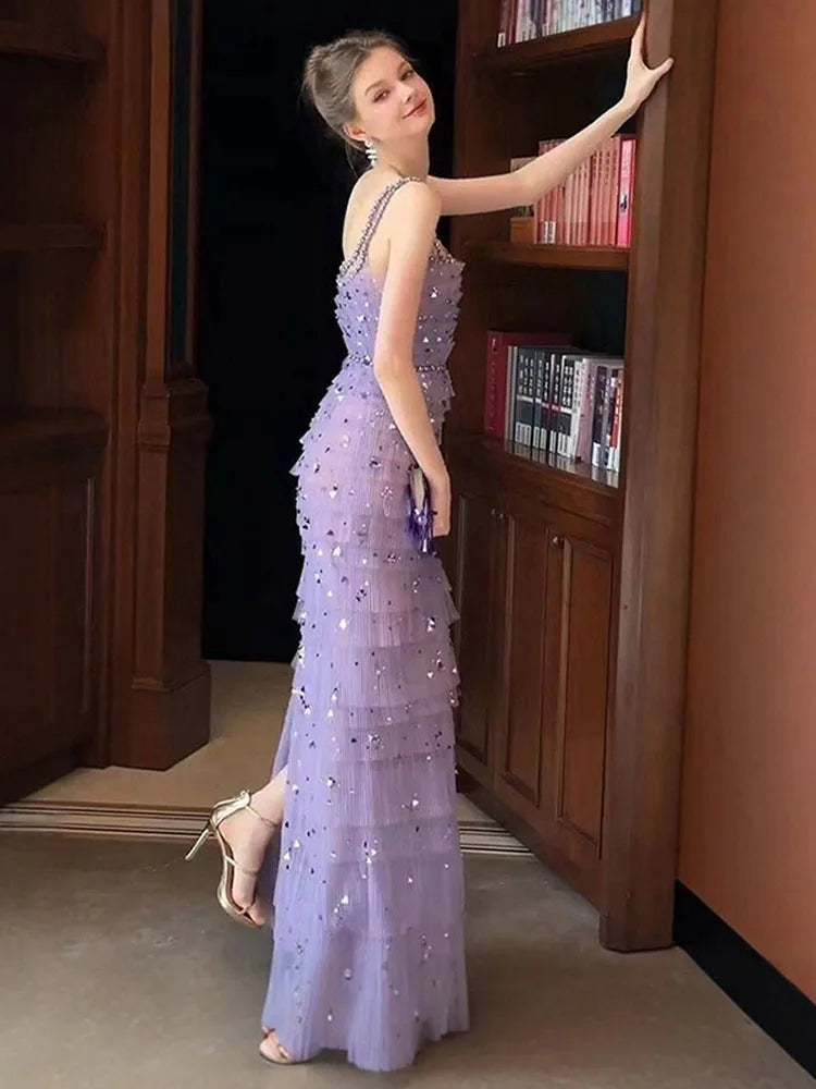 Woman in a purple beaded gown standing next to a bookshelf.
