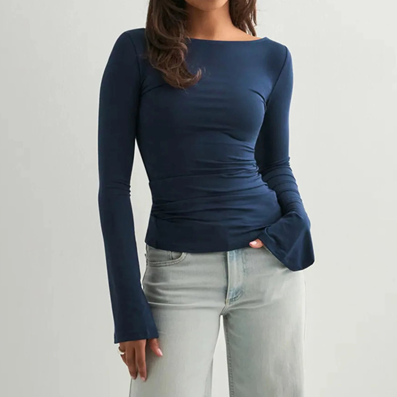 Person wearing a navy blue long-sleeve top and light blue jeans on a plain background