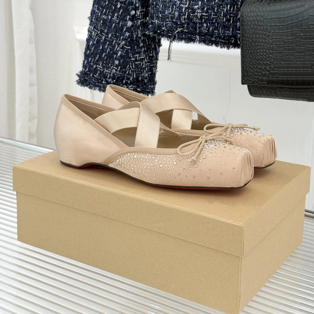 Pair of beige shoes with rhinestone details on a beige box.