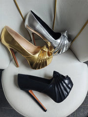 Gold and silver platform stiletto peep toe heels arranged on a chair.