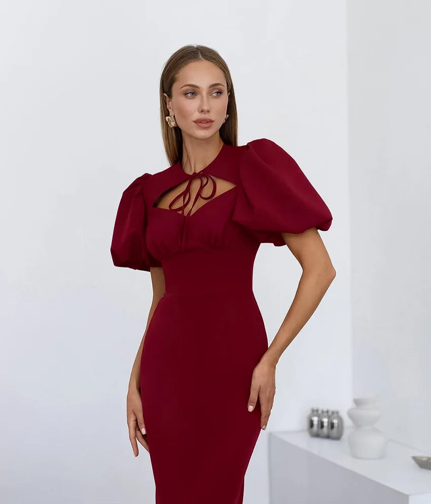 Woman wearing a burgundy dress with puff sleeves against a white background