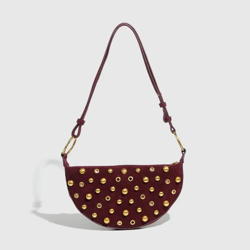 Maroon handbag with gold studs on a light gray background
