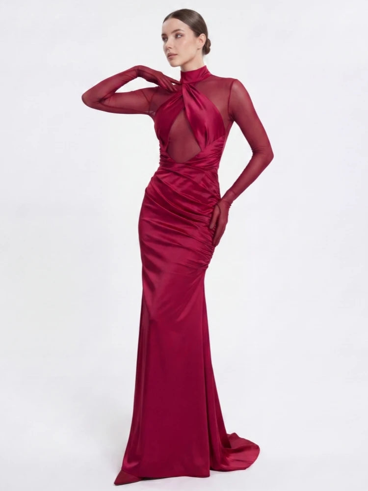 Woman posing in a claret ruched maxi dress with mesh neckline and gloves