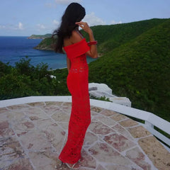 Woman in a red dress standing on a stone patio with a scenic view of the ocean and hills.