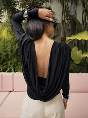 Person wearing a black open-back top with a blurred background