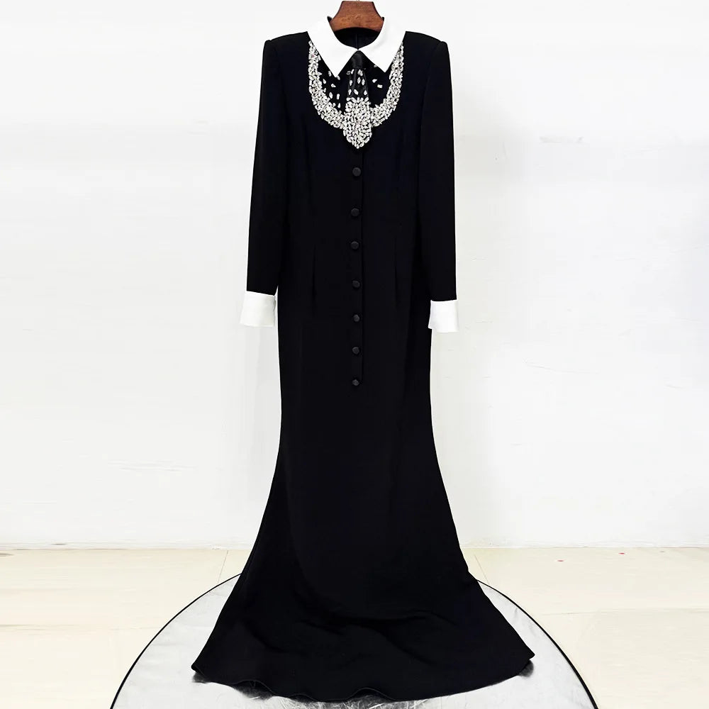 Black floor-length dress with white collar and beaded embellishment hanging on a display.