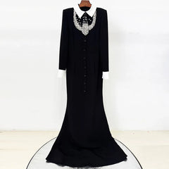 Black floor-length dress with white collar and beaded embellishment hanging on a display.