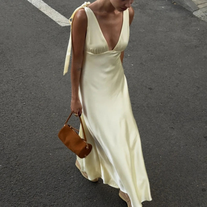 Woman in a long, light-colored dress walking on a street.