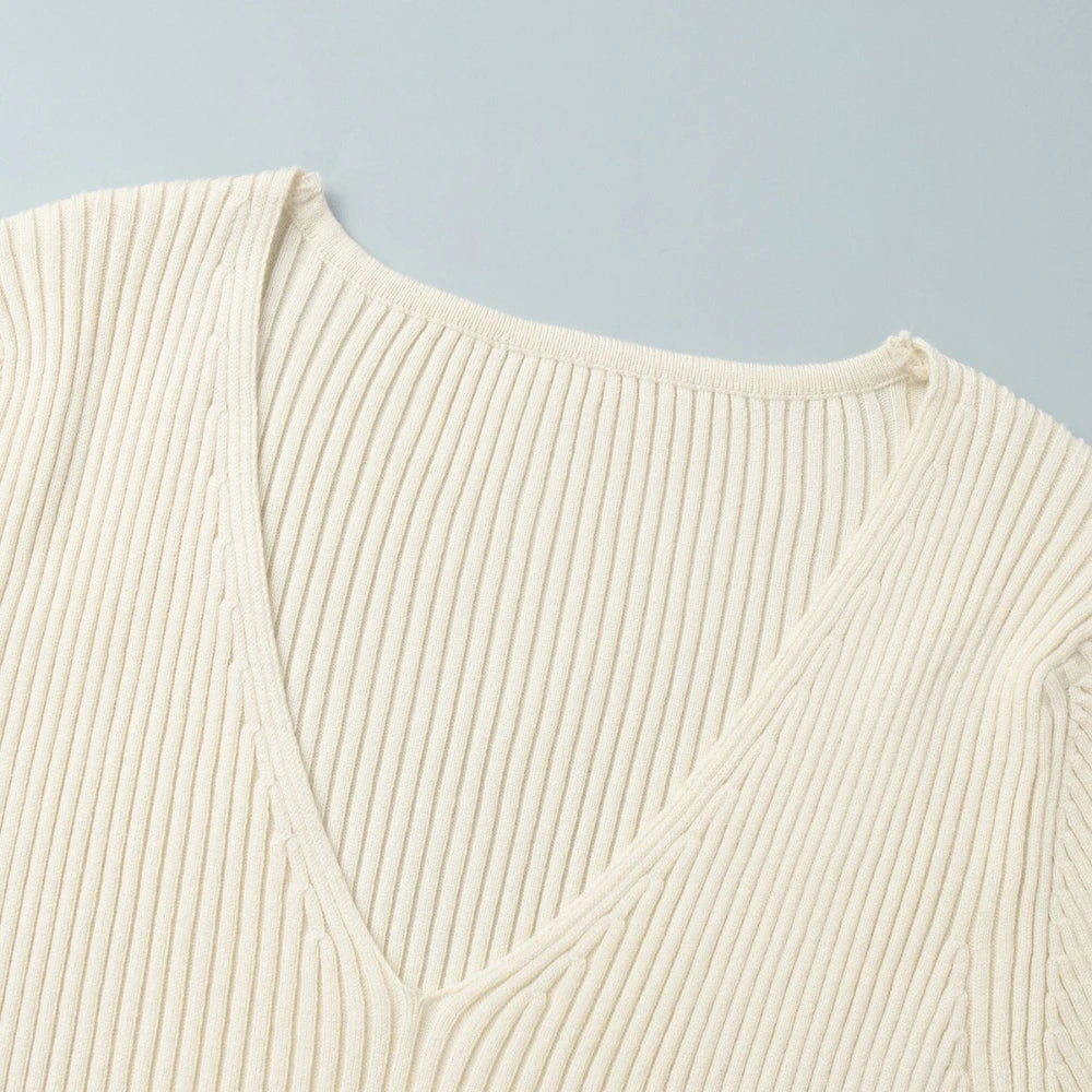 Close-up of a cream-colored ribbed sweater on a light blue background