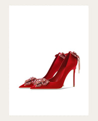 Red high-heeled shoes with decorative bows on a white background